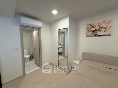 Modern bedroom with ensuite bathroom and mirrored wardrobe in stylish apartment.