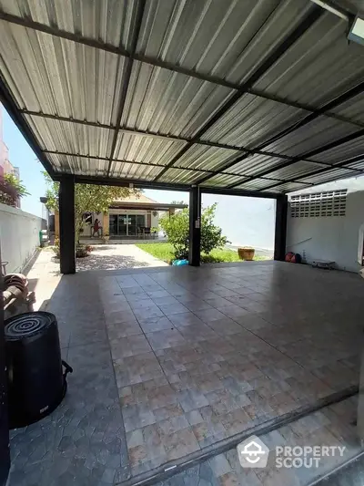 Spacious covered parking area with tiled flooring and garden view