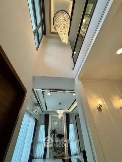 Luxurious high-ceiling interior with elegant chandelier and large windows