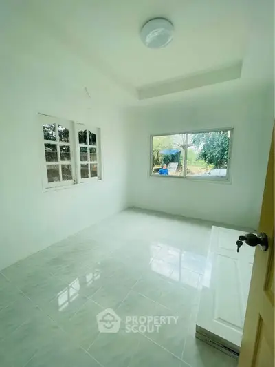 Bright empty room with large windows and white tiled flooring, perfect for customization.