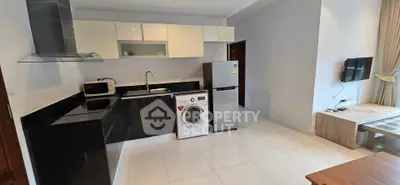 Modern kitchen with sleek black and white cabinetry, washing machine, and stainless steel fridge.