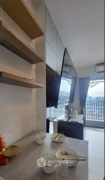 Modern living room with sleek TV setup and city view balcony, perfect for urban living.
