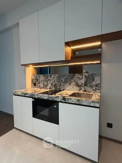 Modern kitchen with sleek cabinetry and marble countertops in a stylish apartment.