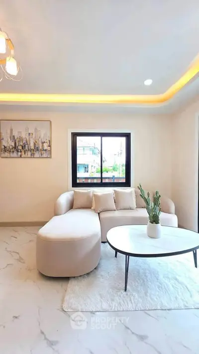 Modern living room with stylish furniture and large window offering natural light.