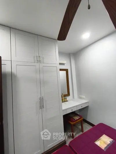 Cozy bedroom with built-in wardrobe and dressing table, perfect for compact living spaces.