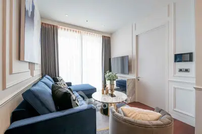 Elegant living room with plush blue sofas, modern decor, and natural light from large windows.