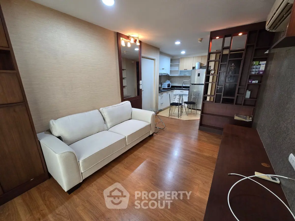 Spacious living room with modern kitchen in open layout, featuring elegant wooden flooring and stylish furniture.
