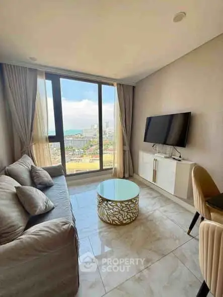 Modern living room with large window and stylish furniture, offering a stunning city view.