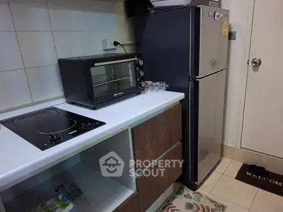 Modern kitchen with sleek appliances, featuring a compact oven and stylish fridge.