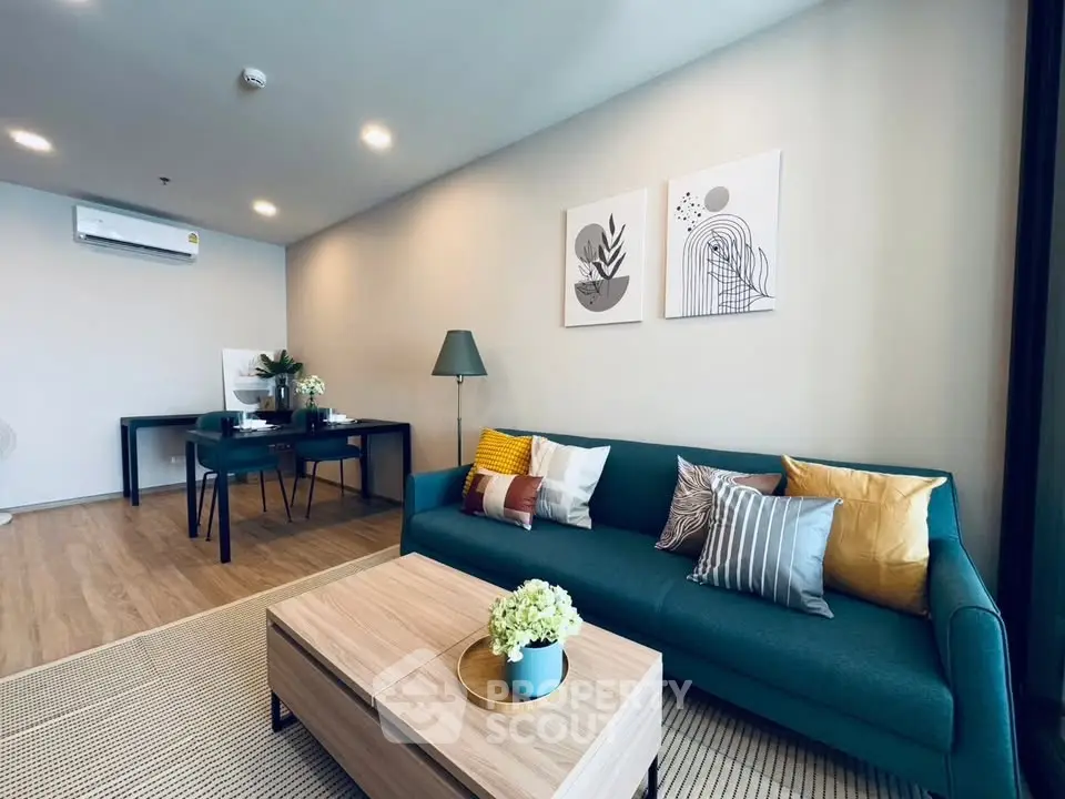 Modern living room with stylish decor, featuring a teal sofa, wooden coffee table, and contemporary artwork.
