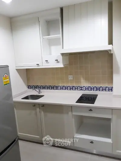 Modern kitchen with sleek cabinetry and electric cooktop in a compact layout.