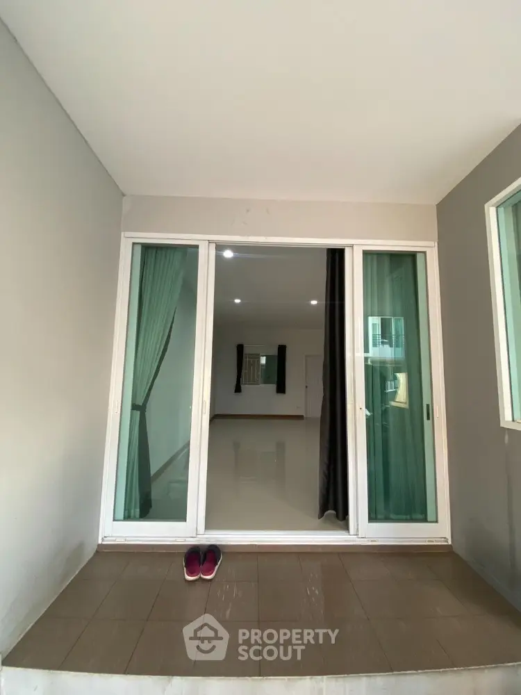 Spacious and bright room with large sliding glass doors leading to a cozy balcony, featuring clean lines and a neutral color palette for a modern living space.