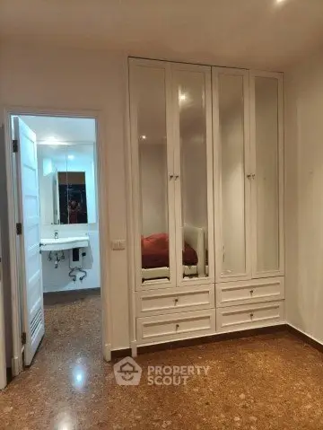 Spacious bedroom with built-in wardrobe and view into modern bathroom