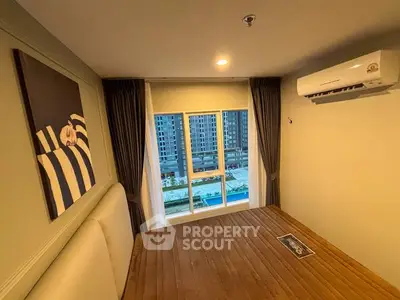 Modern bedroom with large window and air conditioning, overlooking cityscape.