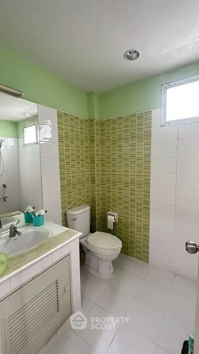 Modern bathroom with green accent tiles and natural light
