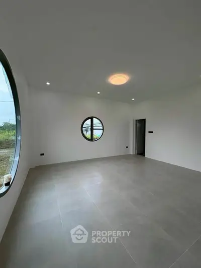 Spacious modern room with unique circular windows and minimalist design.