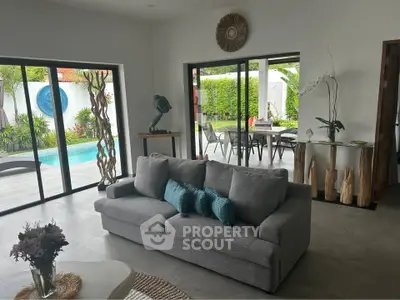 Spacious living room with pool view, modern decor, and large glass doors opening to patio.