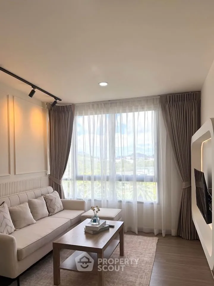Elegant living room with large windows and cozy sofa, offering a serene view and natural light.