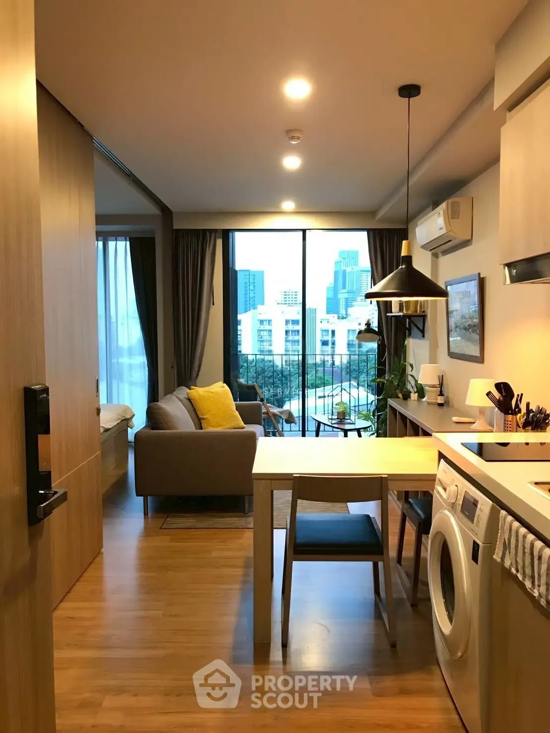 Modern open-plan apartment with city view, featuring cozy living area and kitchen with washing machine.