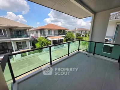 Spacious balcony with glass railing offering a scenic neighborhood view, perfect for relaxation and outdoor enjoyment.