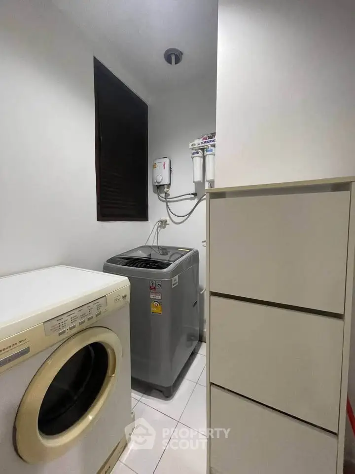 Compact laundry room with washing machine and storage cabinets in modern apartment.
