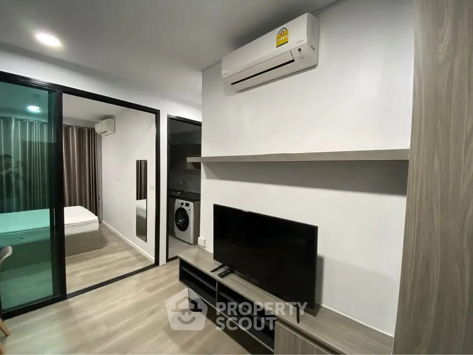 Modern apartment interior with sleek design, featuring a cozy living area, air conditioning, and a glimpse of the bedroom.