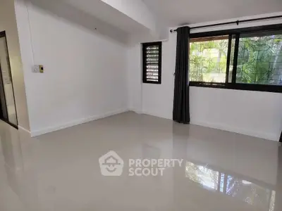 Spacious empty room with glossy tiled floors and large windows for natural light.