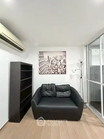 Modern living room with black sofa, bookshelf, and cityscape artwork.