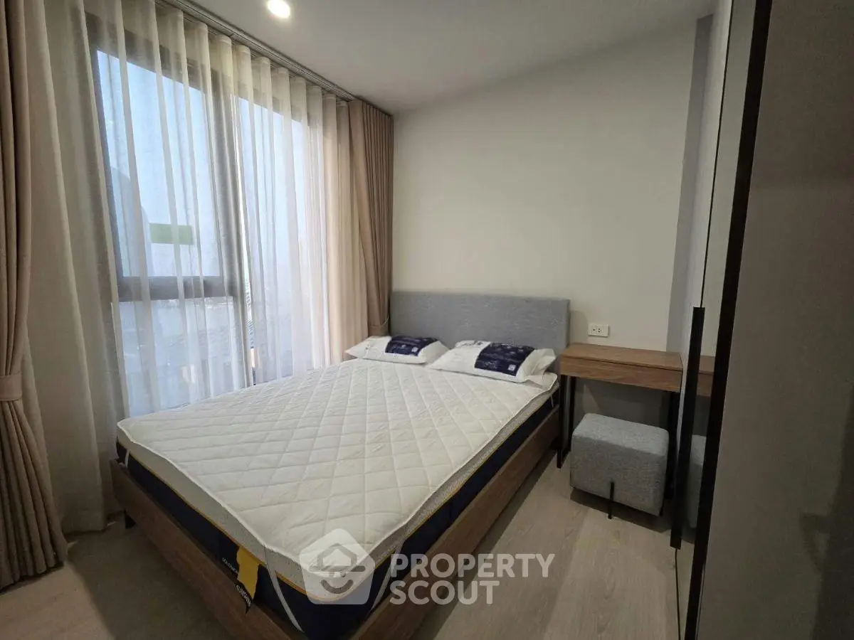 Modern bedroom with large window and stylish furnishings in a contemporary apartment.