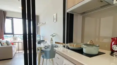 Modern kitchen with open layout and cozy living area, featuring sleek appliances and stylish decor.