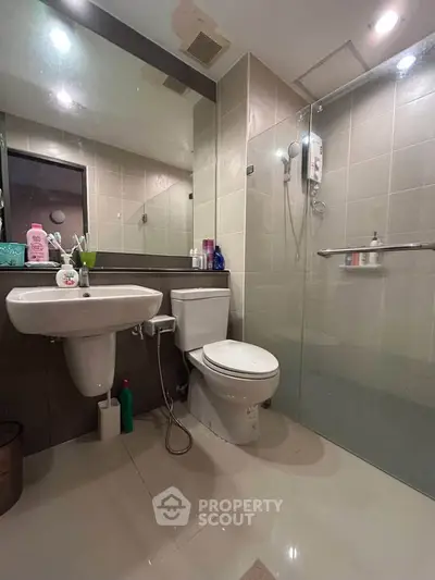 Modern bathroom with glass shower and sleek fixtures in contemporary apartment.