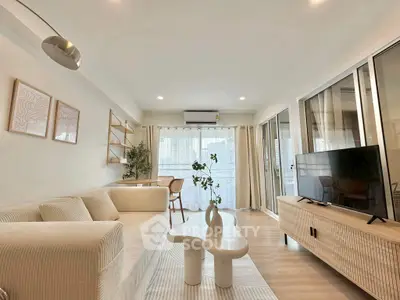 Modern living room with cozy sofa, stylish decor, and large windows offering natural light.