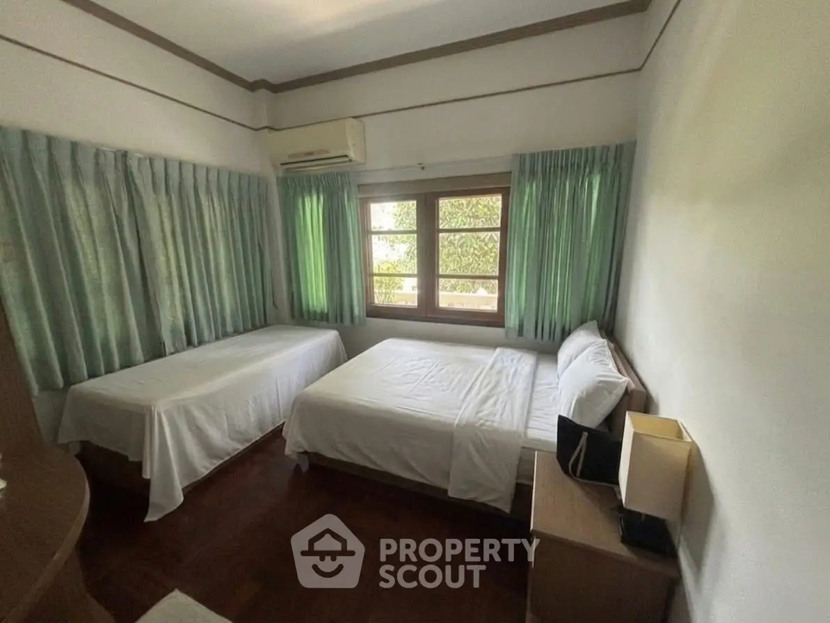 Cozy bedroom with twin beds, air conditioning, and natural light from large window.