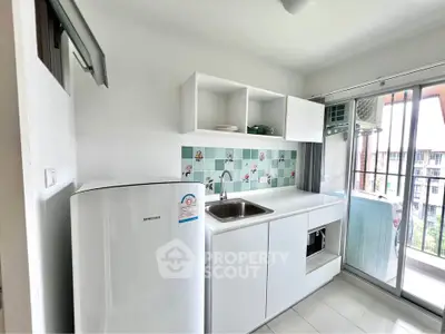 Modern kitchen with balcony view, featuring sleek white cabinets and tiled backsplash.
