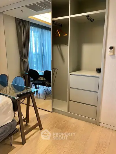 Modern bedroom with built-in wardrobe and glass desk, featuring floor-to-ceiling window for natural light.