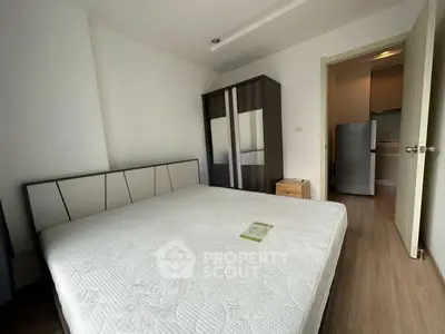 Spacious bedroom with modern furnishings and adjacent kitchen area in a stylish apartment.