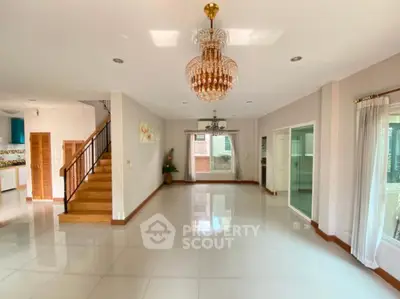 Spacious living room with elegant chandelier and staircase in modern home