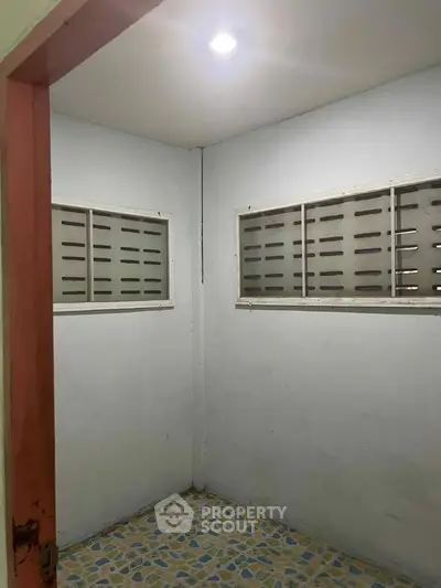 Small room with tiled floor and barred windows, ideal for storage or utility use.