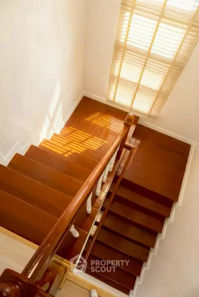 Elegant wooden staircase with natural light streaming through blinds