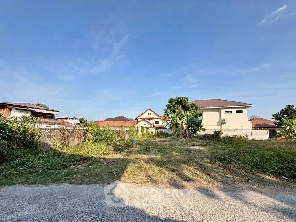 Spacious land plot with potential for development, surrounded by residential homes and scenic views.