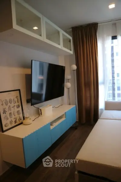 Modern living room with sleek TV setup and stylish decor in urban apartment.