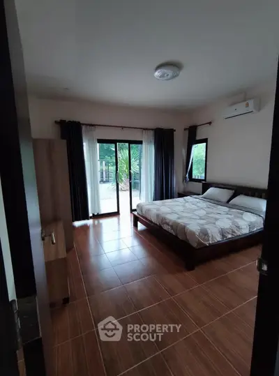 Spacious bedroom with large windows and modern decor in a serene setting.