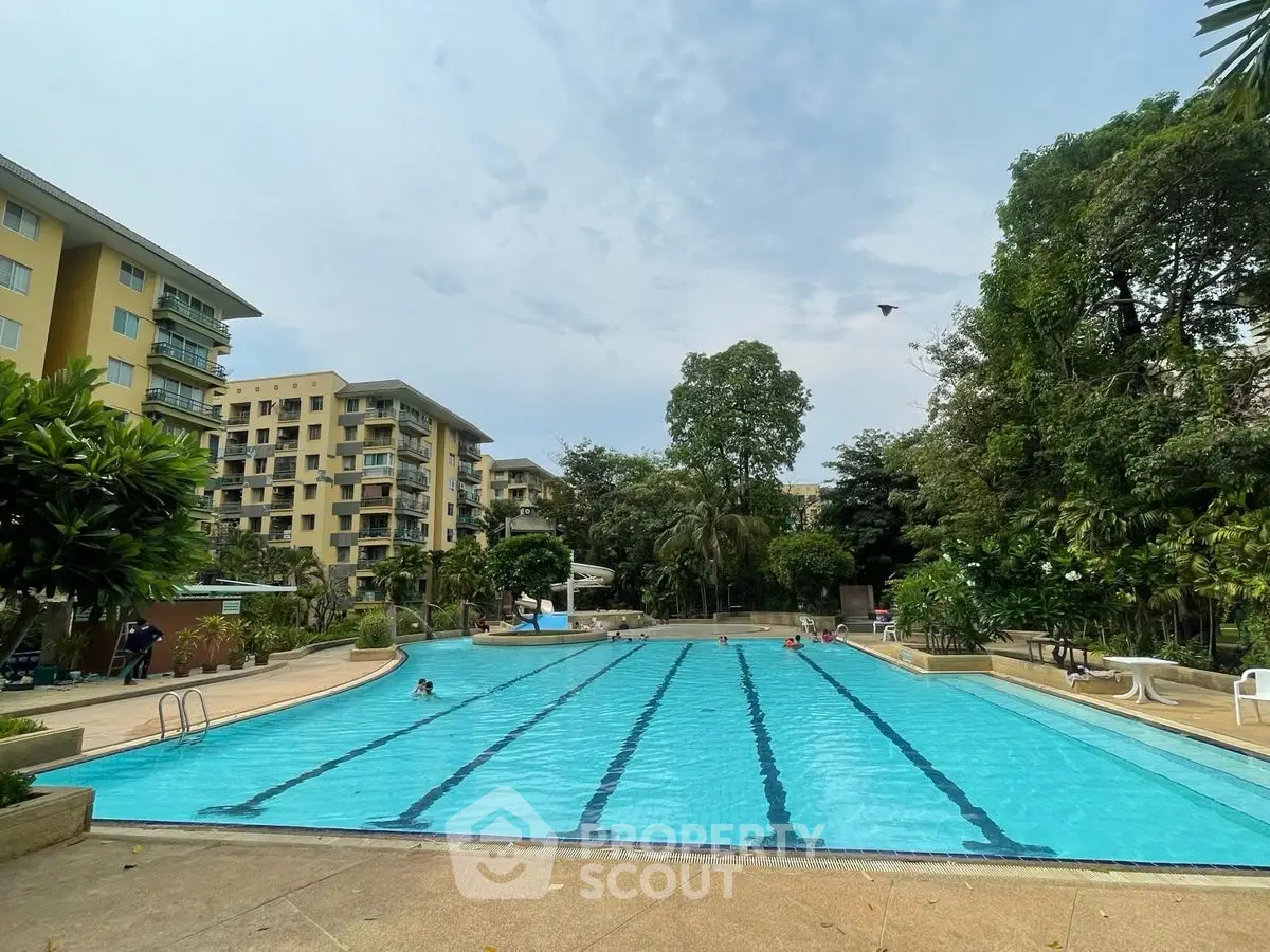 Luxurious residential complex with a large swimming pool and lush greenery.