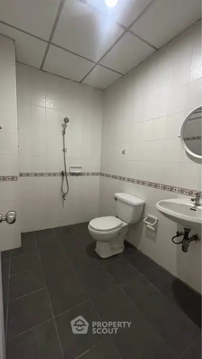Spacious bathroom with modern fixtures and tiled walls, featuring a shower and toilet.