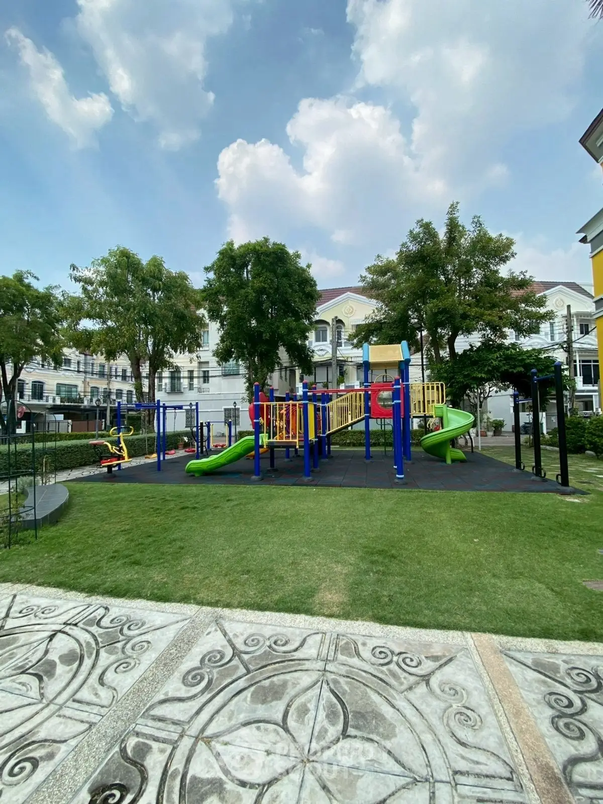 Charming residential playground with vibrant slides and lush greenery, perfect for family-friendly living.