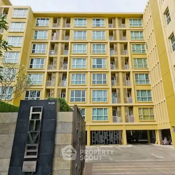 Modern yellow apartment building with multiple balconies and secure entrance.