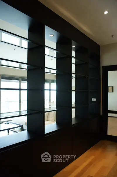 Modern living room with sleek black shelving and hardwood floors, offering a stylish and functional space.