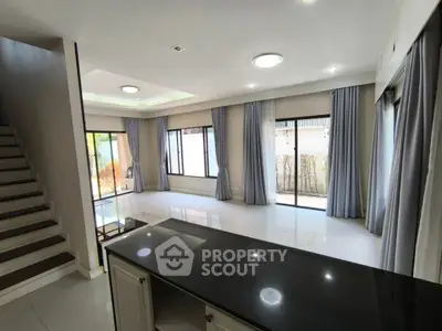 Spacious modern living room with large windows and elegant staircase in a contemporary home.