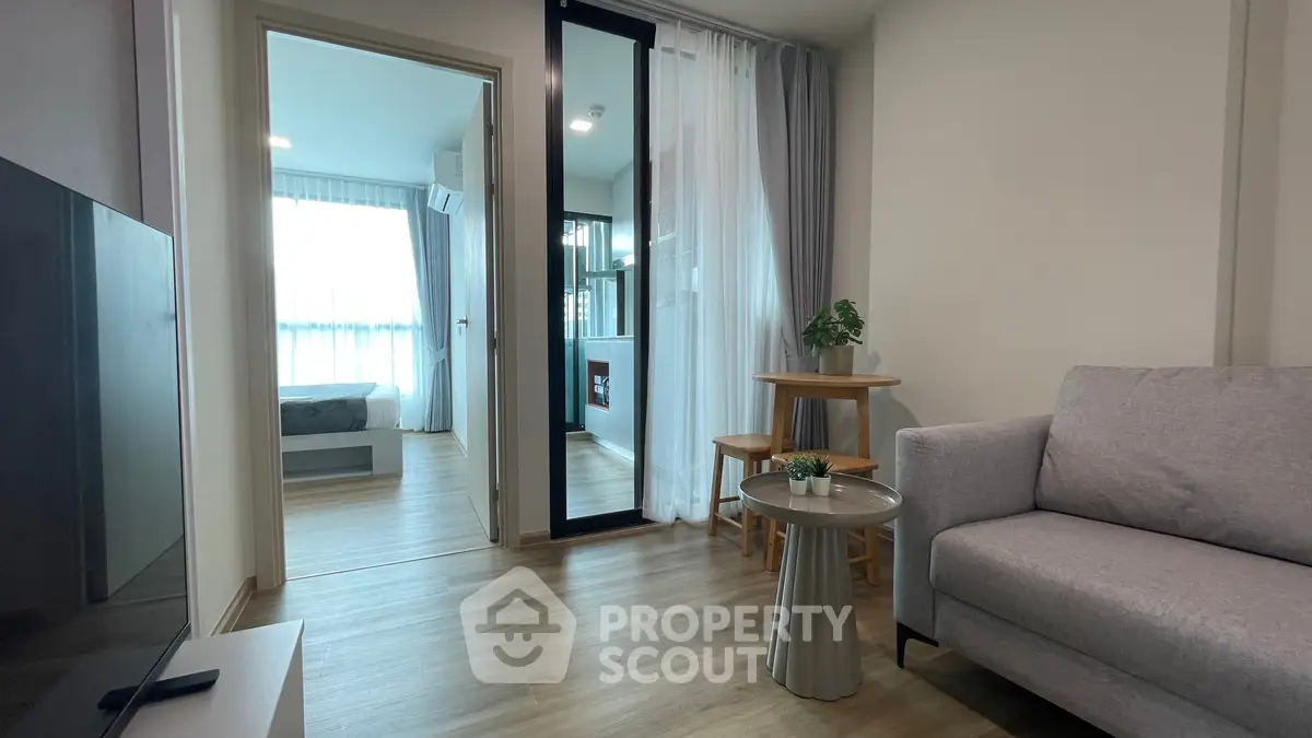 Modern apartment interior with cozy living room and view into bedroom, featuring stylish decor and natural light.