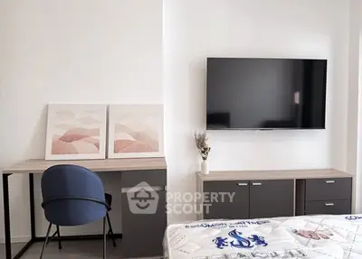 Modern bedroom with sleek TV setup and stylish desk area, perfect for urban living.